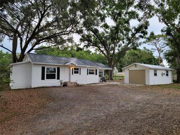 Charming home with white siding, black shutters, metal roof, and detached garage at 5535 Peach Ave, Seffner, FL 33584