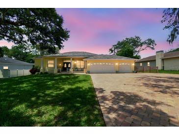 Charming single-story home with a three-car garage, landscaped yard, and inviting front porch at 10306 Shalimar Wood Dr, Thonotosassa, FL 33592
