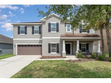 Charming two-story home with well-manicured lawn, covered porch with pillars and an attached two-car garage at 11206 Coventry Grove Cir, Lithia, FL 33547