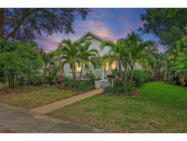Charming home with mature tropical landscaping, lush green lawn and a welcoming walkway leading to the front porch at 1211 14Th N St, St Petersburg, FL 33705