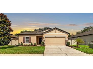 Charming one-story home featuring a well-manicured lawn, neutral tan paint, and a two-car garage at 12428 Chaya Ct, Spring Hill, FL 34610
