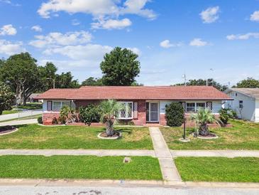 Charming single-story home featuring a well-maintained lawn and mature landscaping under a sunny sky at 1436 Santa Clara Dr, Dunedin, FL 34698