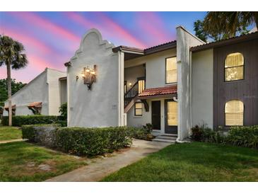 Inviting condo exterior with stucco walls, red roof tiles, manicured landscaping and warm accent lighting at dusk at 3505 Tarpon Woods Blvd # P404, Palm Harbor, FL 34685