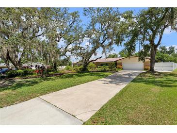 Charming home featuring a long driveway, lush lawn, and mature trees, providing a welcoming entrance at 708 Westwood Cir, Brandon, FL 33511