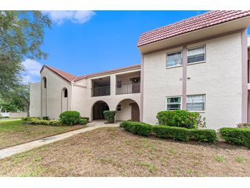 Charming condo featuring well-maintained landscaping, a red tile roof, and inviting archway at 9700 Starkey Rd # 312, Seminole, FL 33777