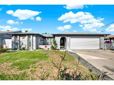 Charming single-story home with a well-maintained lawn, arched entry, and a two-car garage under a bright blue sky at 13926 Darlene Ave, Hudson, FL 34667