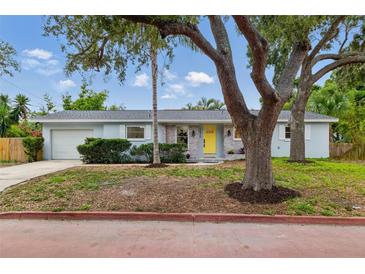 Charming single-story home featuring a bright yellow front door, brick accents, and lush landscaping at 1470 Serpentine S Dr, St Petersburg, FL 33705