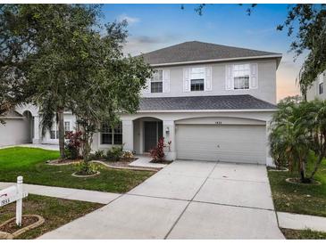 Charming two-story home featuring a well-manicured lawn, neutral paint, shutters, and an attached two-car garage at 1933 Fruitridge St, Brandon, FL 33510