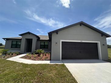 Charming single-story home with a dark garage door, complemented by a manicured lawn and blue sky at 2330 Hiers Rd, Dover, FL 33527