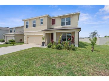 Two-story home featuring a two-car garage, manicured lawn, and colorful flowers, offering classic curb appeal at 30936 Summer Sun Loop, Wesley Chapel, FL 33545