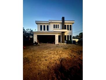 Modern two-story home with dark-trimmed windows and attached garage with unfinished landscaping at dusk at 4101 W Mango Ave, Tampa, FL 33616