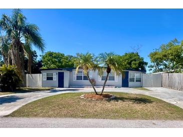 Charming single-story home featuring a well-manicured lawn, circular driveway, and mature palm trees at 10367 109Th Ave, Largo, FL 33773