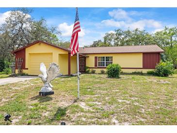 Charming single-Gathering home featuring a well-maintained lawn and an American flag in the front yard at 14339 Mayer Ave, Hudson, FL 34669