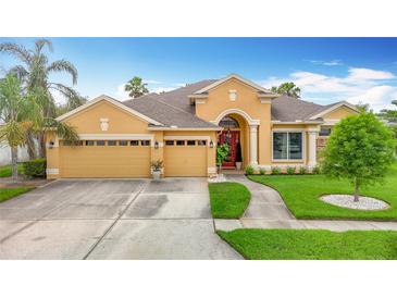 Inviting single-story home features a three-car garage, red front door, and manicured landscaping at 1443 Obear Ct, Wesley Chapel, FL 33543