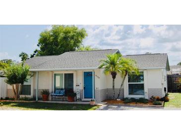 Charming single-story home boasts a bright blue front door, lush landscaping, and a welcoming front porch with seating at 9128 Suffield Ct, Tampa, FL 33615
