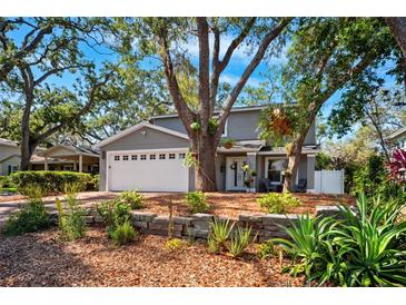 Charming two-story home with a well-manicured lawn, garden beds, and mature trees creating a shaded front yard at 1120 43Rd N Ave, St Petersburg, FL 33703