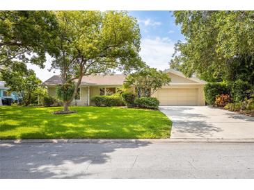 Charming single-story home features a well-manicured lawn, mature trees, and a two-car garage at 1235 Nelson St, Dunedin, FL 34698