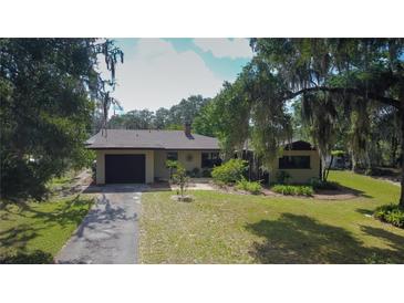 A charming single-story home with a well-maintained front yard and an attached garage, framed by mature trees at 34389 Orchid Pkwy, Ridge Manor, FL 33523