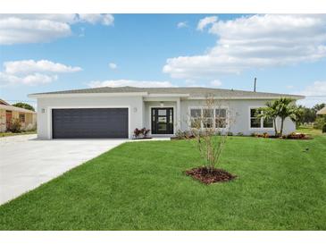 Charming single-story home boasts a lush lawn, dark gray garage door, and modern front door at 718 Desert Hills Way, Sun City Center, FL 33573
