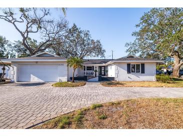 Charming single-story home featuring a white brick facade, well-manicured landscaping, and a paved driveway at 8296 33Rd N Ave, St Petersburg, FL 33710