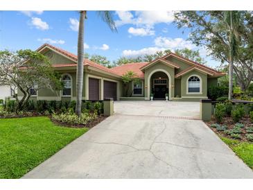 Charming single-story home featuring lush landscaping, a terracotta roof, and an attached two-car garage at 9075 Waterash N Ln, Pinellas Park, FL 33782