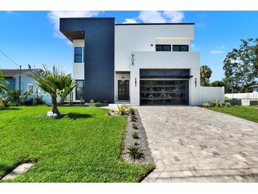 Modern two-story home featuring a black and white exterior with a glass garage door and a well-manicured front yard at 908 W Fribley St, Tampa, FL 33603