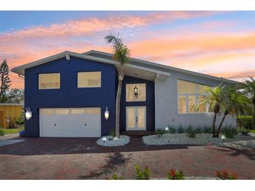 Stunning two-story home with a brick driveway, well-manicured landscaping, and a white two car garage at 931 Gulf Blvd, Belleair Beach, FL 33786