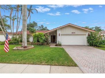 Charming single-story home with a well-manicured lawn, mature trees, and brick driveway at 9674 104Th Ave, Largo, FL 33773