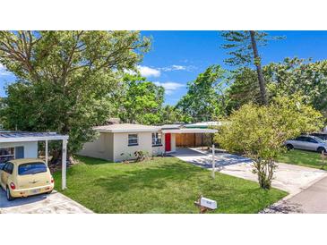 Charming single-story home featuring a well-maintained lawn, carport, and inviting red front door at 10184 117Th Dr, Largo, FL 33773