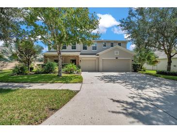 Beautiful two-story home featuring a three-car garage, a manicured lawn, and mature trees at 10833 Breaking Rocks Dr, Tampa, FL 33647