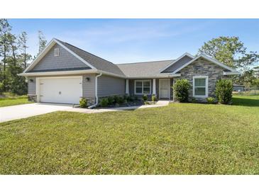 Charming single-story home featuring stone accents, a two-car garage, and a well-manicured lawn at 13227 Quigley Ave, Weeki Wachee, FL 34614