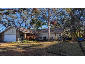 Charming single-story home with mature trees, stone accents, and attached two-car garage at 2033 Aaron Pl, Clearwater, FL 33760