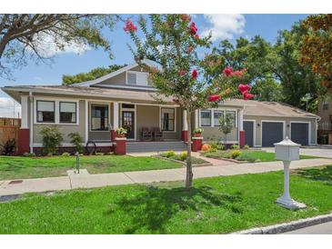 Charming home with a well-manicured lawn, brick accents, and a covered front porch with rocking chairs at 4913 N Central Ave, Tampa, FL 33603