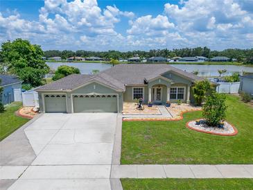 Well-maintained home showcasing a three-car garage, beautiful landscaping, and serene lake view at 6425 Clair Shore Dr, Apollo Beach, FL 33572