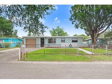 Charming single-story home with a fenced front yard and a well-maintained lawn, complemented by mature trees and a blue sky at 660 11Th N Ave, Safety Harbor, FL 34695