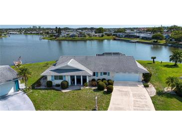 Waterfront property features a well-manicured lawn and an attached two-car garage at 1009 Andover Cir, Sun City Center, FL 33573