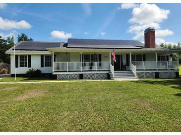 Charming single-story home featuring a welcoming front porch and solar panels for energy efficiency at 17430 Spring Valley Rd, Dade City, FL 33523