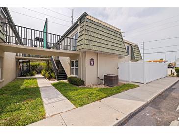 Inviting condo exterior featuring manicured lawn, white picket fence, black iron stairway, and assigned parking at 1799 N Highland Ave # 3, Clearwater, FL 33755