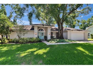 Charming one-story home featuring a light exterior, manicured lawn, mature trees, and a welcoming light blue front door at 1905 Horseshoe Dr, Plant City, FL 33566
