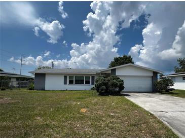 Charming single-story home featuring an attached garage, mature landscaping, and a well-maintained front yard at 2195 Academy Dr, Clearwater, FL 33764