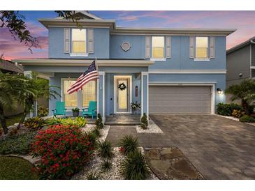 Beautiful blue two-story home with an inviting front porch, complemented by lush landscaping and a two car garage at 4770 Ballantrae Blvd, Land O Lakes, FL 34638