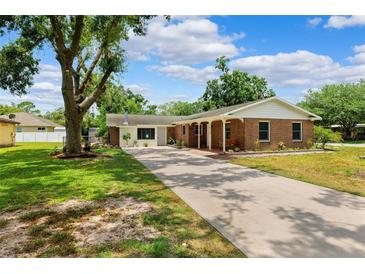 Charming single-story brick home with a long driveway, mature landscaping, and a covered front porch at 509 Falmouth St, Temple Terrace, FL 33617