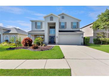 Two-story home with a well-manicured lawn and a two-car garage on a sunny day at 7732 Bulls Head Dr, Wesley Chapel, FL 33545