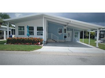 Charming single-story home features a covered carport, blue siding, and vibrant landscaping at 119 Dolphin S Dr, Oldsmar, FL 34677