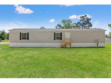 Charming gray home with green lawn and black shutters on a sunny day at 16070 La Bella St, Brooksville, FL 34604