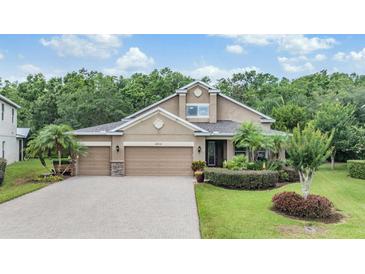 Beautiful home with a well-manicured lawn, a three-car garage, and lush landscaping at 19312 Sunset Bay Dr, Land O Lakes, FL 34638