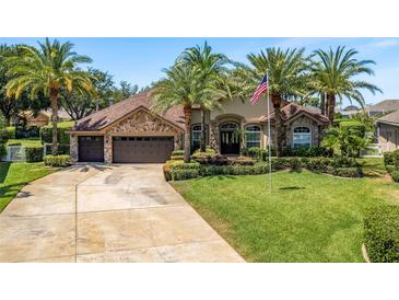 Charming home exterior with lush lawn, mature palms, stone accents, and three-car garage at 2041 Gold Dust Ct, Trinity, FL 34655