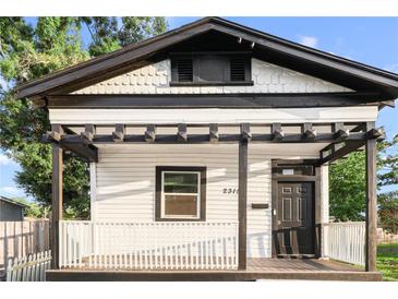 Charming home exterior features a covered porch with pergola, a black front door and white picket fence at 2315 E 12Th Ave, Tampa, FL 33605