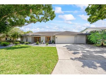 Charming single-story home featuring a tile roof, manicured lawn, and lush landscaping at 2900 Sandpiper Pl, Clearwater, FL 33762