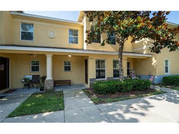 Inviting townhome exterior featuring a covered porch, manicured landscaping, and classic architectural details at 37712 Aaralyn Rd, Zephyrhills, FL 33542